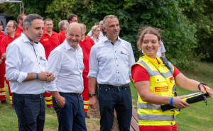 Der Bundeskanzler mit Manuel Friedrich, Präsident der DLRG Bayern Bildmitte), und Einsatzleiterin Jacqueline Gläsener  